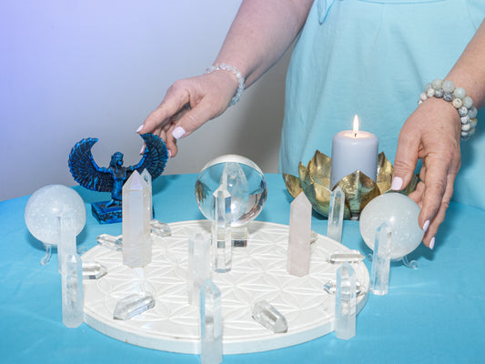 Különböző méretű és színű kristályok rendezve fekszenek egy fa asztalon, természetes fényben megvilágítva